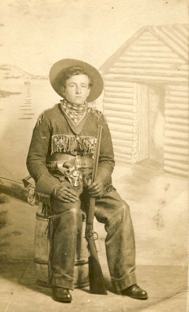 Man with rifle sitting on a barrel postcard