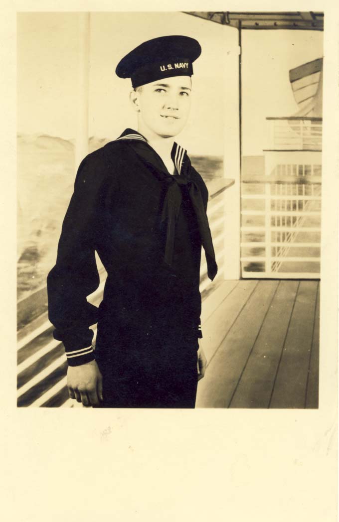 U.S. sailor standing in front of false navy studio setting postcard