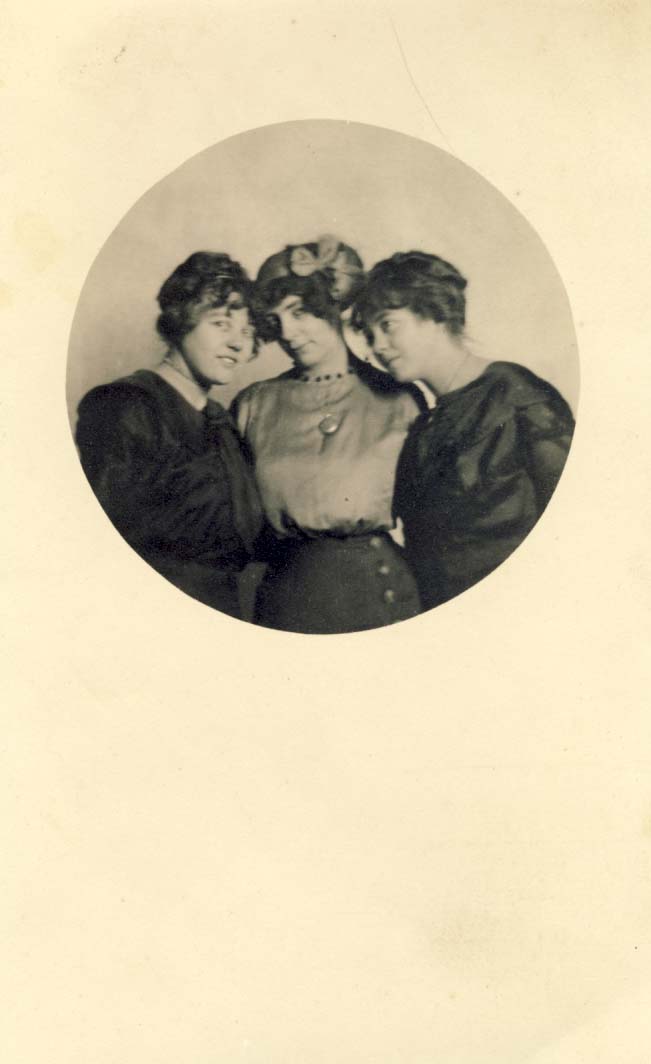 Three women, heads together, one wearing a locket postcard