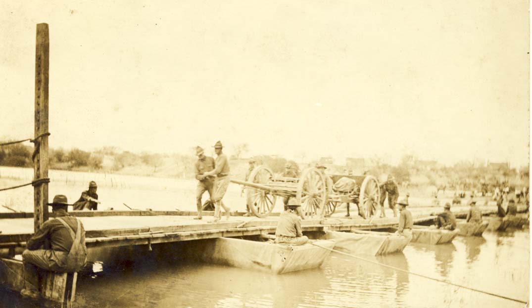 Men pulling wagon across pontoon bridge postcard