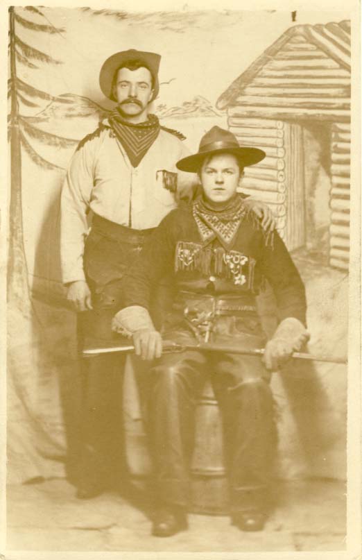 Two men, one standing with hand on the other's shoulder, real photo postcard 1900s