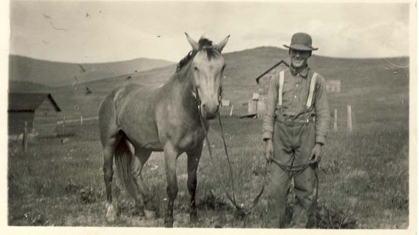 Man in hat wearing suspenders, holding horse reins postcard