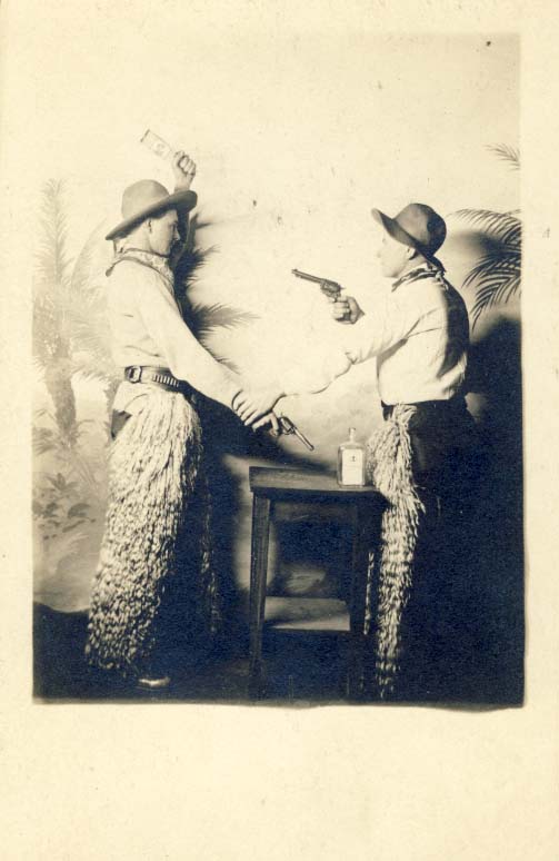 2 men, both in chaps, one with bottle raised postcard